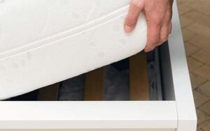 Batzner Pest Control technician performing a bed bug inspection by lifting mattress in Wisconsin home. 