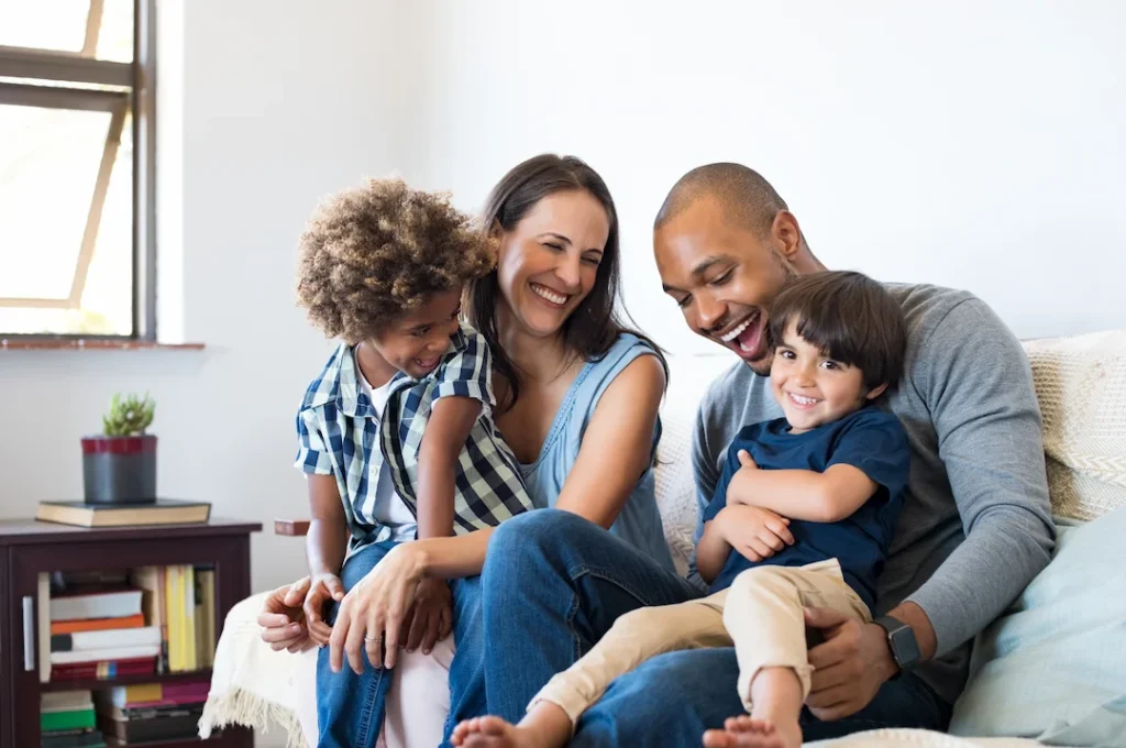 Family of four smiling on a couch in their home - Keep pests away form your home with Batzner Pest Control in WI