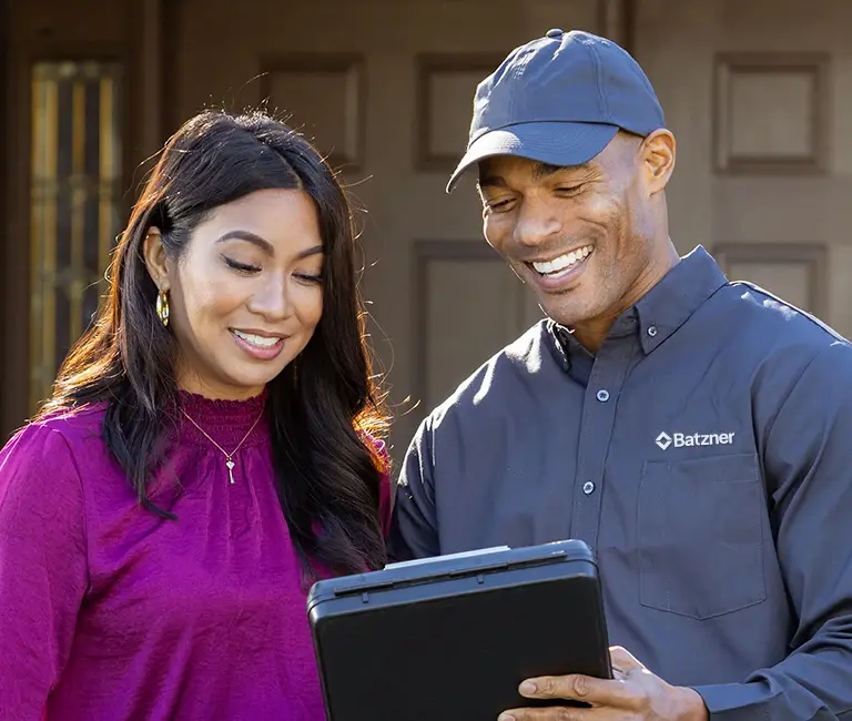 Technician speaking with a homeowner in front of a house | Batzner Pest Control