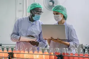 Production line supervisor and worker work together in a beverage processing line