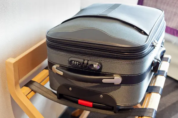 Luggage sitting on a luggage rack in a hotel room.