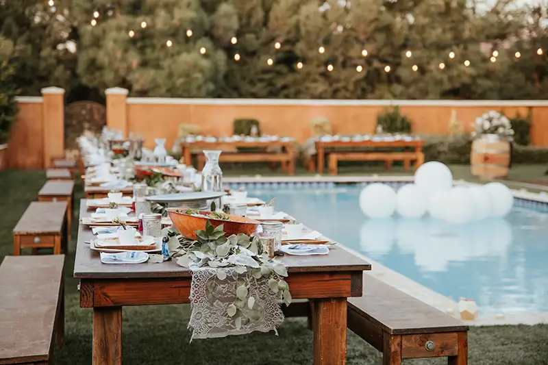 A long dining table next to a pool at a wedding reception. Mosquitoes can be quite the pest when bodies of water, like pools, are present, but Batzner Pest Control can help get rid of them.