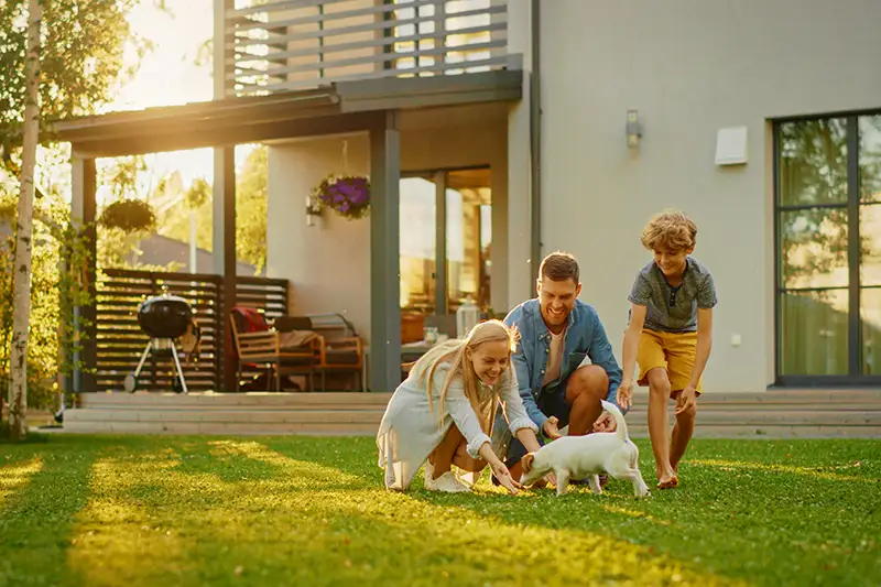 A family playing with a puppy in their backyard after mosquito treatment by Batzner Pest Control
