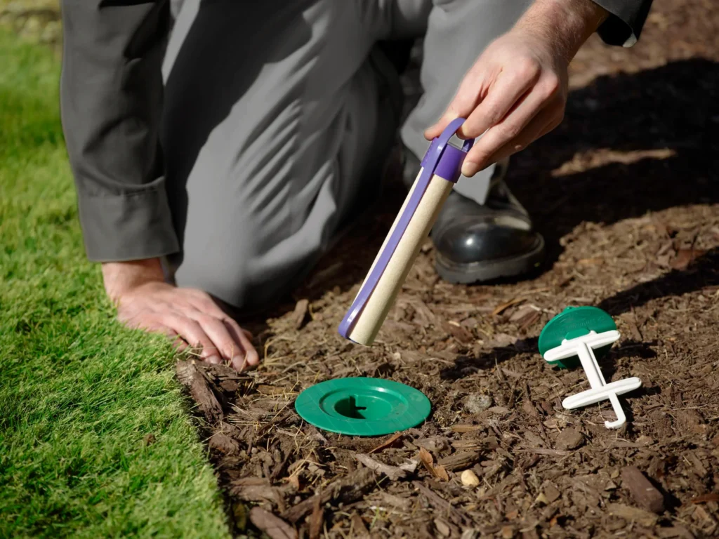 A Batzner Pest Control technician showing what a fresh termite bait station looks like.