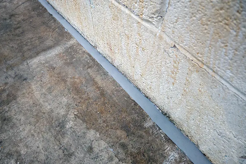Flexi Armour caulking the crack between brick wall & concrete flooring, used by Batzner Pest Control technicians to protect against pests.